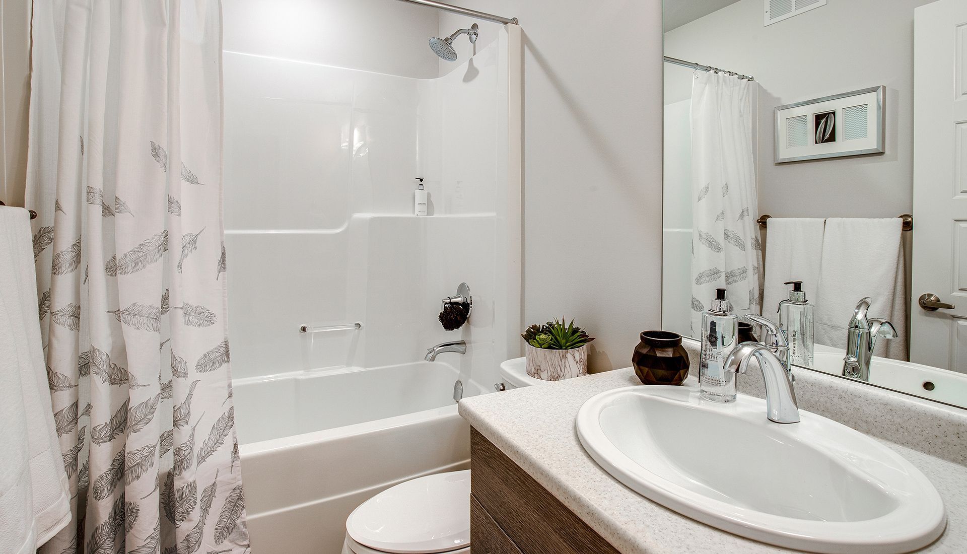 Bathroom with a white tub and sink, a patterned shower curtain, and a framed picture.