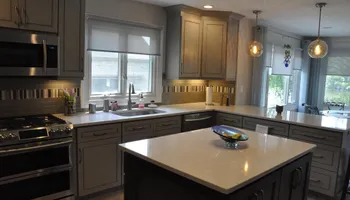 Modern kitchen with gray cabinets, white countertops, and a dark island.