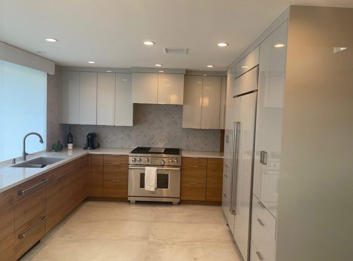 Modern kitchen with white cabinets, gray backsplash, stainless steel appliances, and a large island sink