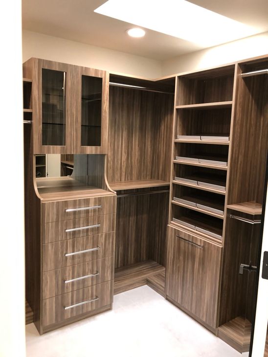 Wood-paneled built-in closet shelves and cabinets in a small corner room