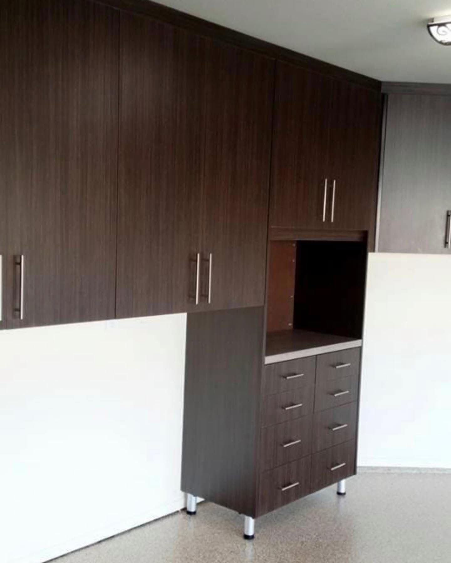 Built-in dark wood cabinets with a small desk nook in a room with white walls