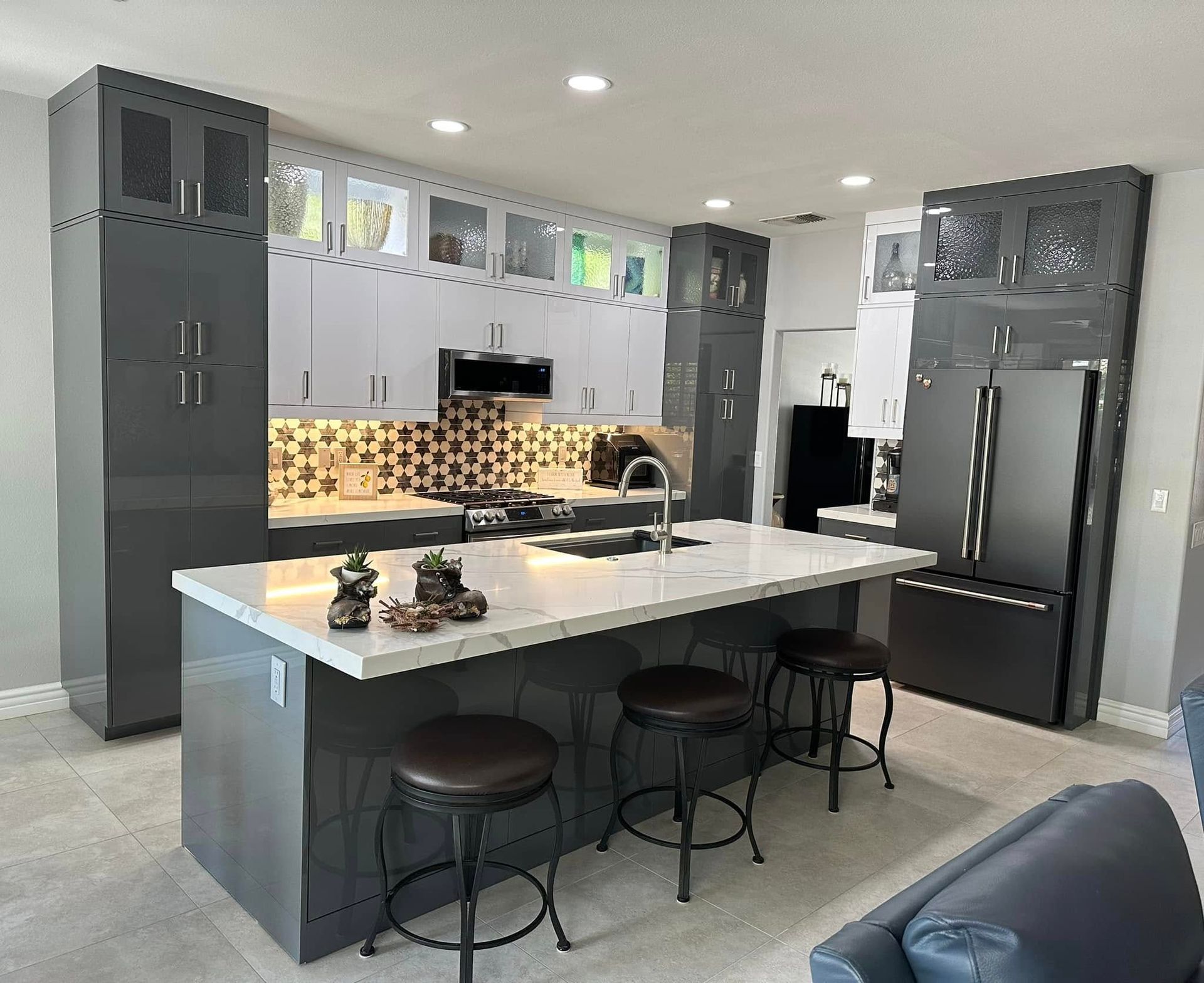 Modern kitchen with dark gray cabinets, large island, bar stools, and stainless steel appliances