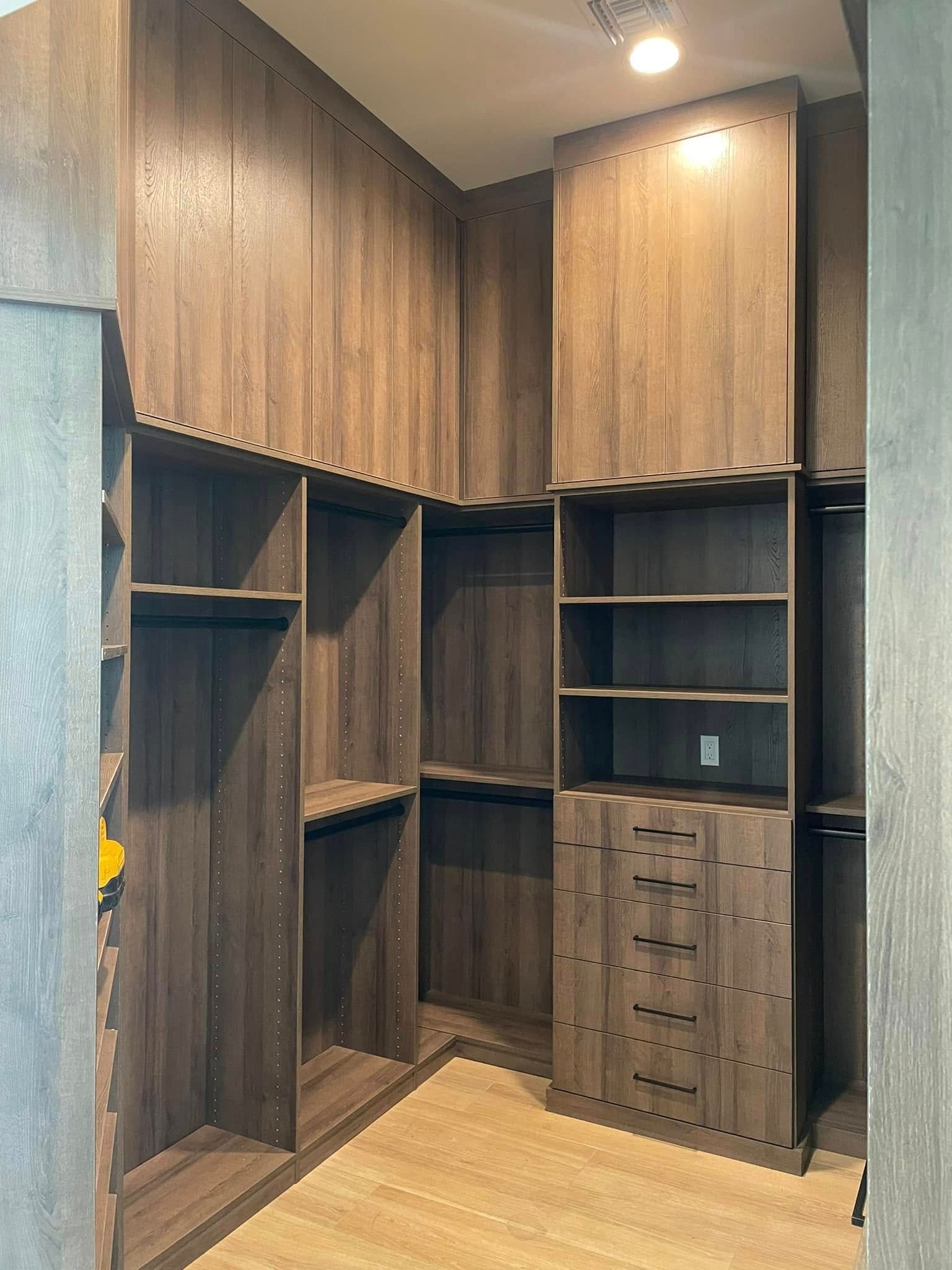 Built-in wood closet with open shelves, hanging spaces, and drawers in a small room.