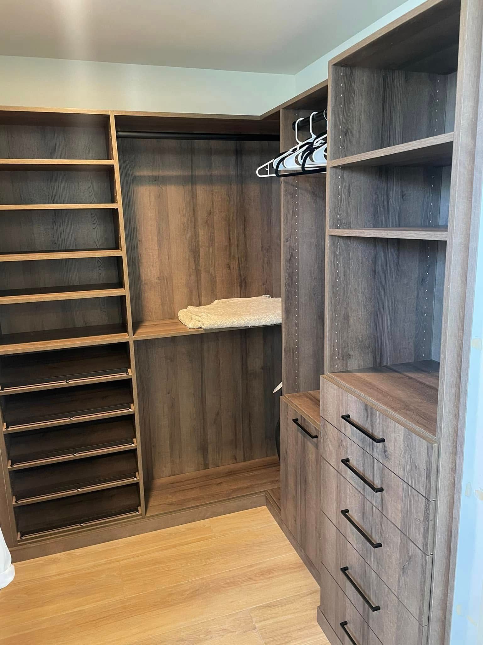 Walk-in closet with wood shelving, hanging space, and drawers on the right.