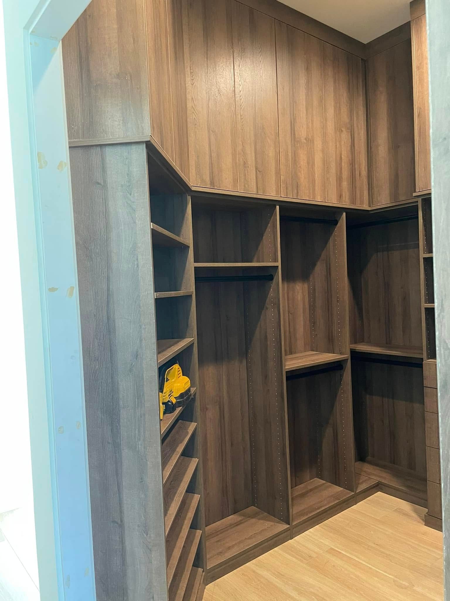 Built-in dark wood storage shelves in a hallway alcove with light wood flooring and a small yellow flower decoration