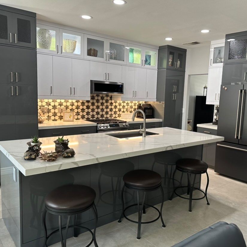 Modern gray kitchen with a large white island, black stools, and patterned backsplash