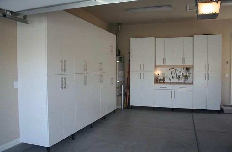 Garage with white storage cabinets and built-in workbench against the back wall.