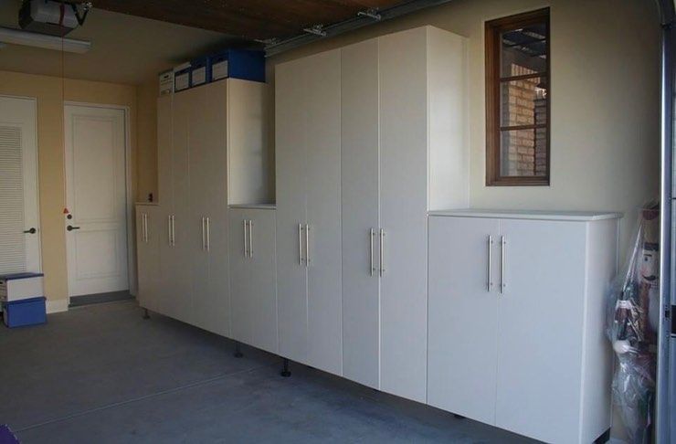 Garage with large white storage cabinets along the wall and a carpeted floor