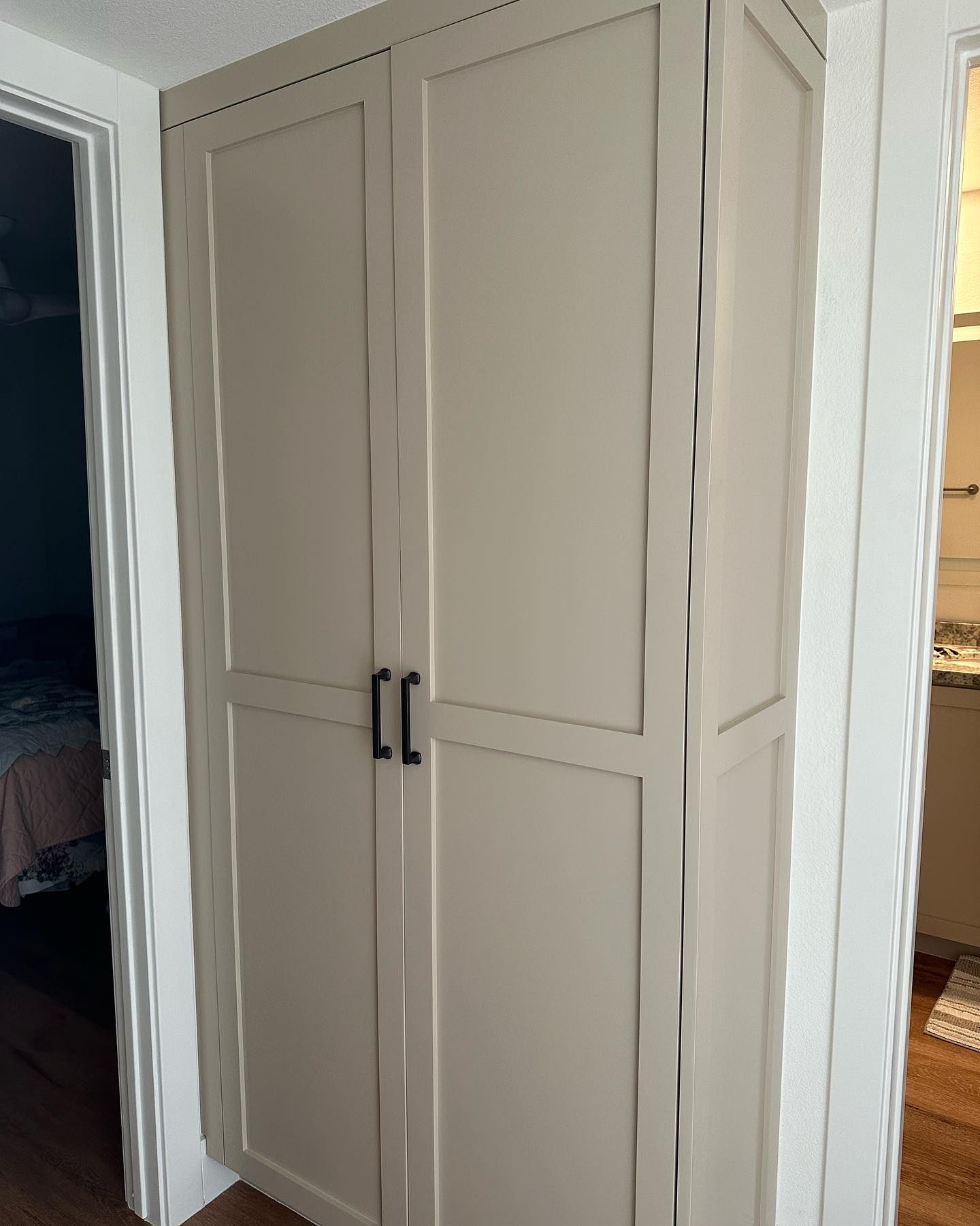 Beige double-door closet in a hallway between two rooms.