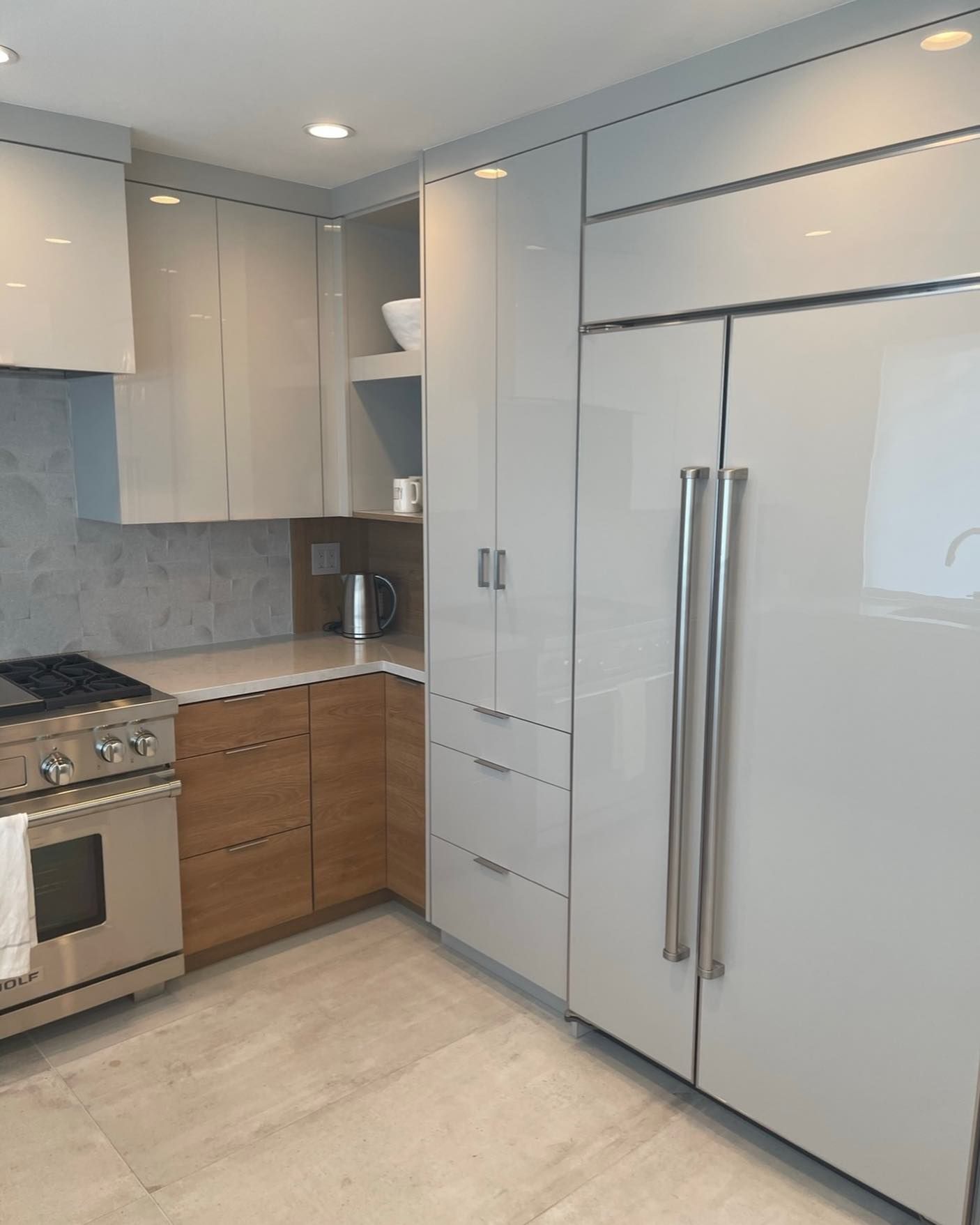 Modern kitchen with white cabinets, stainless steel appliances, and light wood flooring