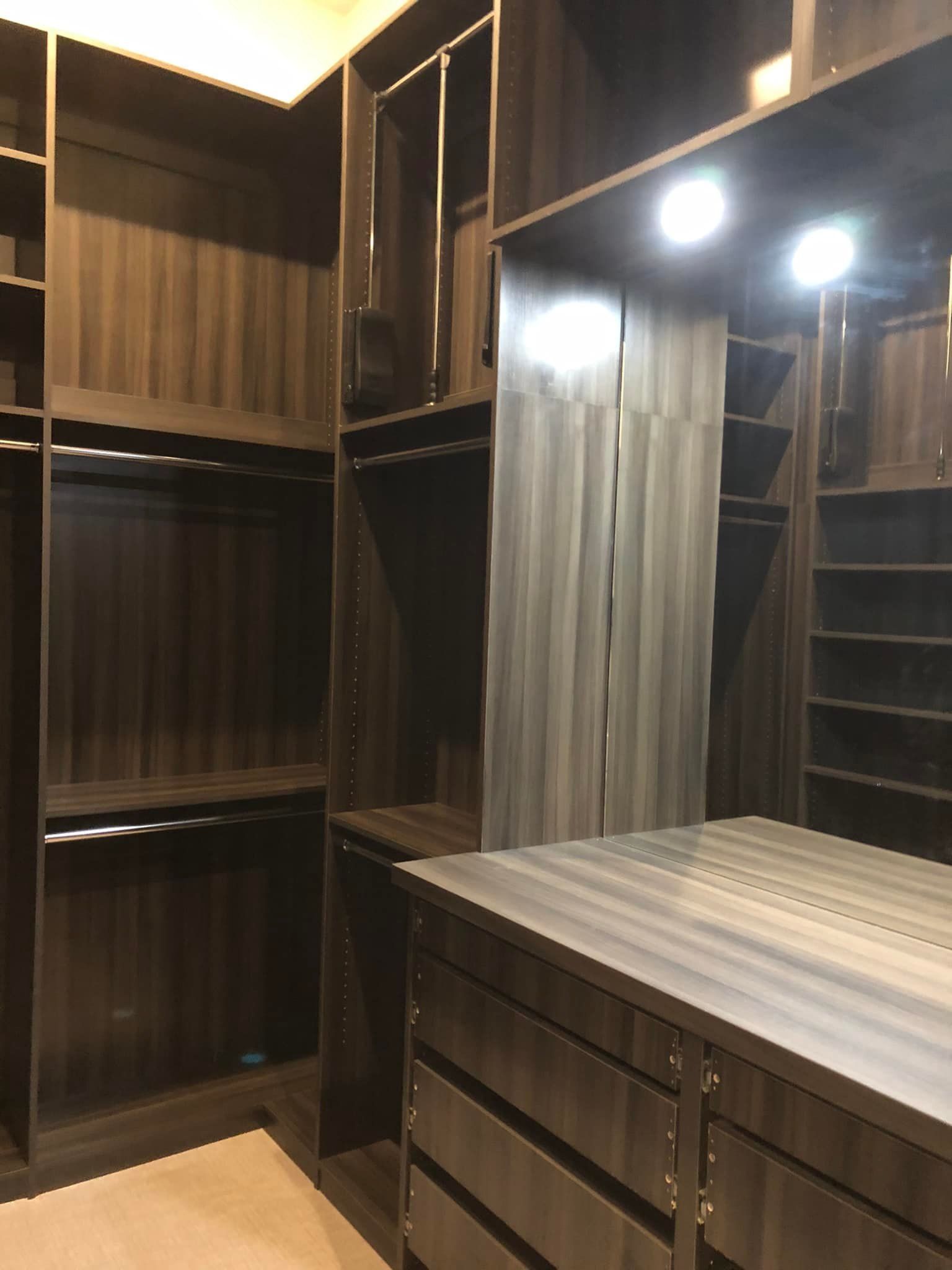 Built-in dark wood closet with mirrored doors, shelves, and drawers in a walk-in dressing room.