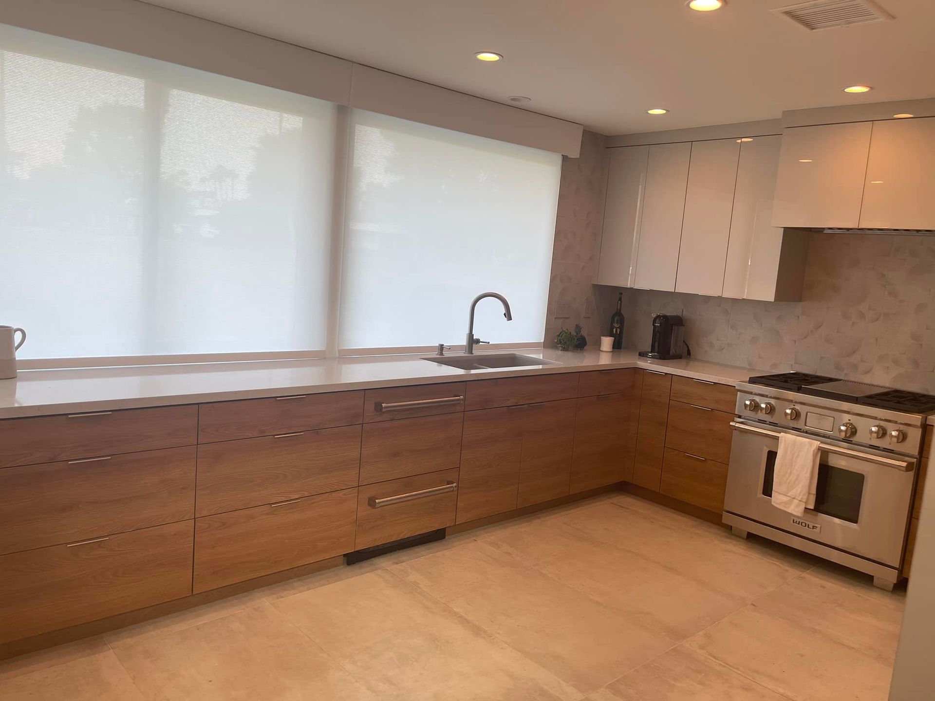 Modern kitchen with wood cabinets, large window, long countertop, sink, and stainless steel stove