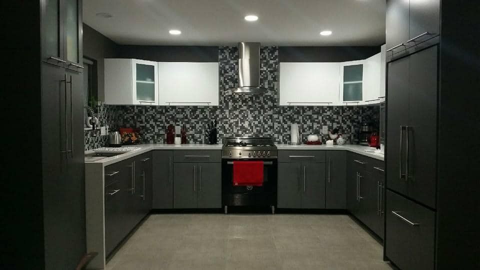 Modern dark kitchen with black cabinets, white upper cabinets, stainless appliances, and a red oven door