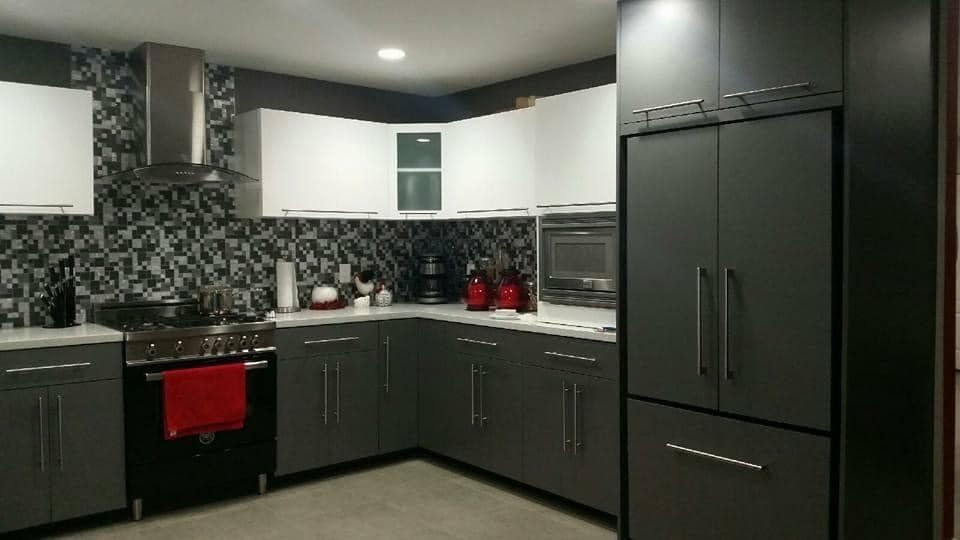 Modern kitchen with dark cabinets, black appliances, patterned backsplash, and red accents