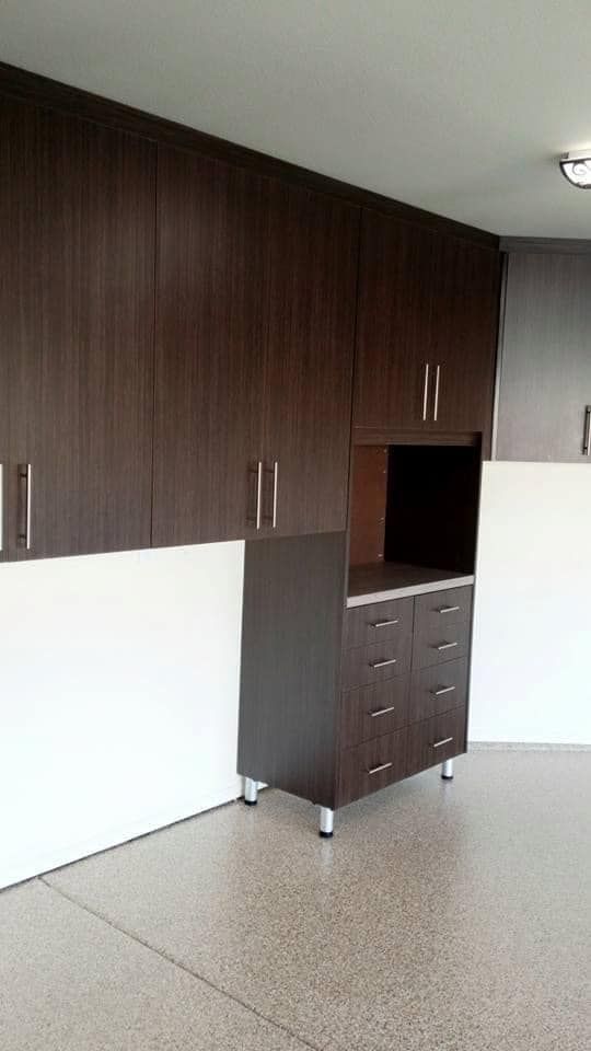 Empty room with dark wood cabinets, white panels, and speckled flooring