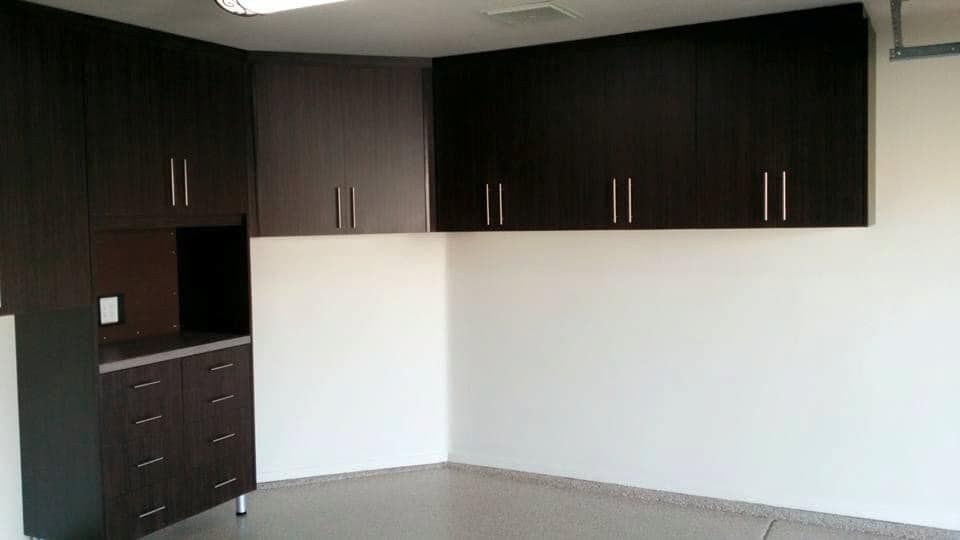 Modern dark-wood cabinets and drawers in an empty white-walled room with gray carpet.