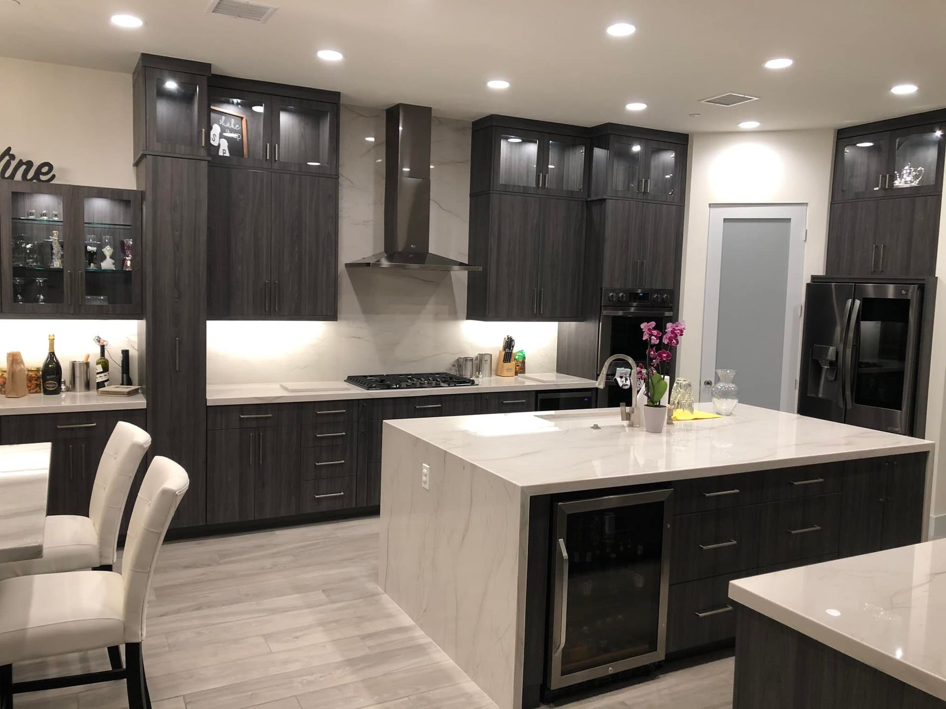 Modern kitchen with dark cabinets, white countertops, island, and recessed lighting