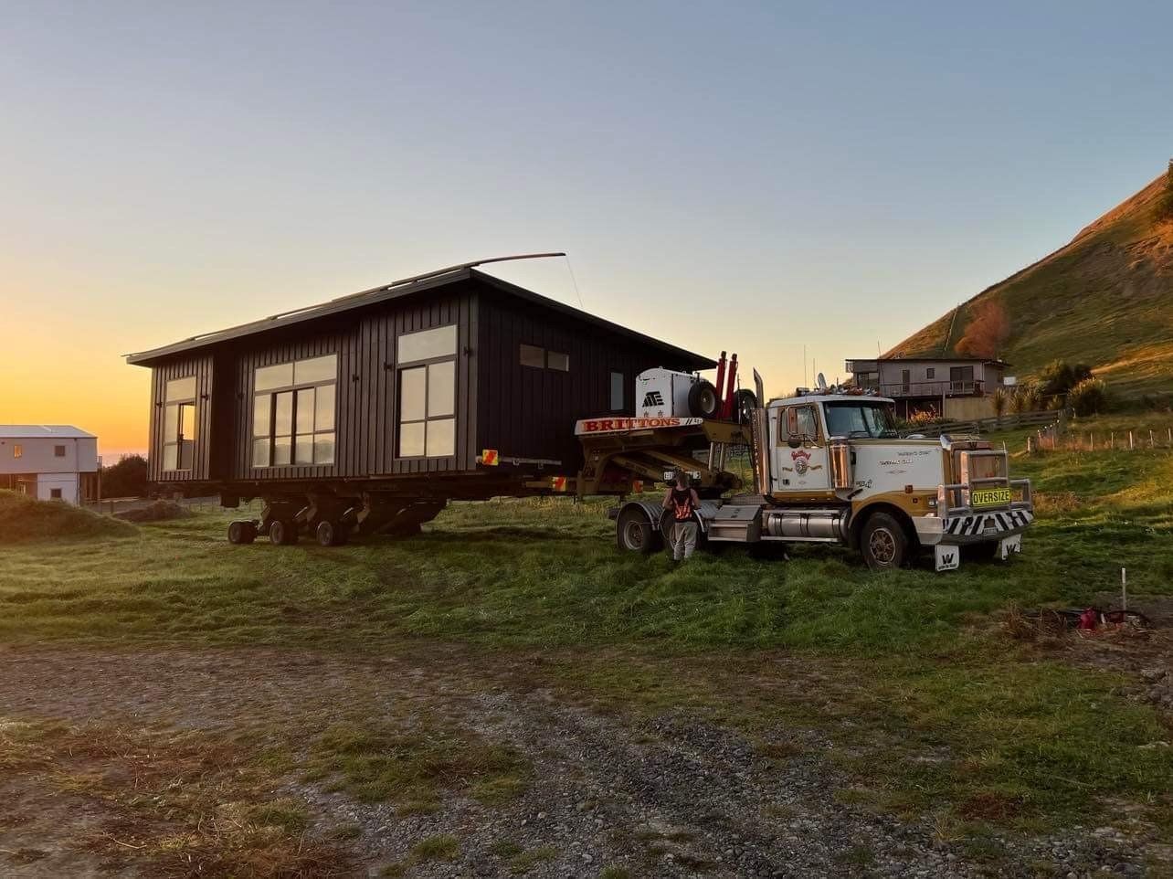 Small house at sunset with an old truck parked beside it on a grassy hillside
