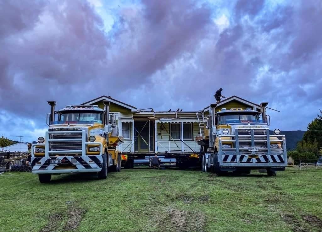 Two large decorated trucks on a grassy field under a cloudy purple sky