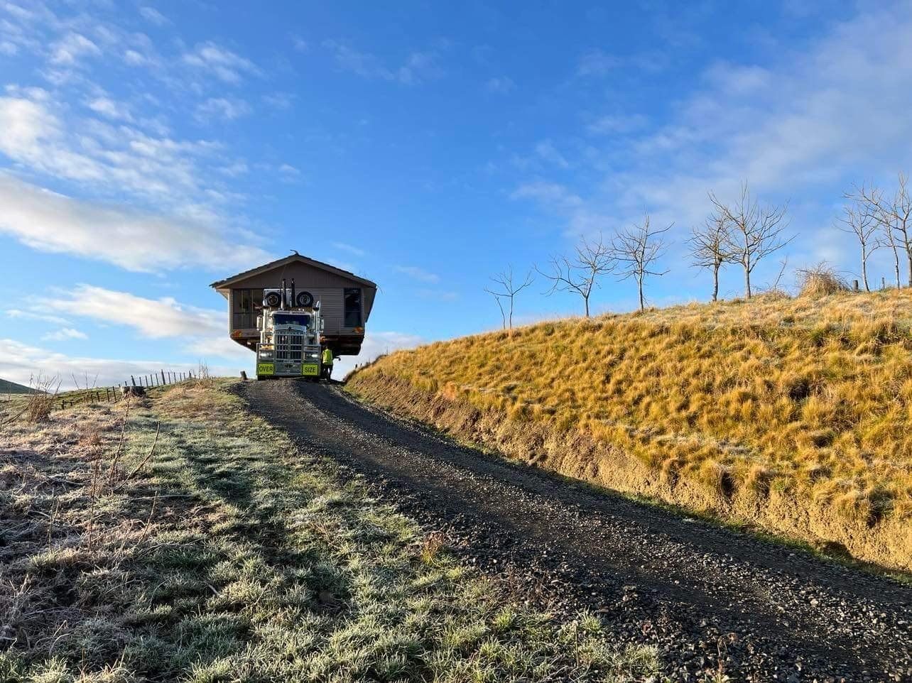 Small cabin at the top of a frosty dirt path under a blue sky