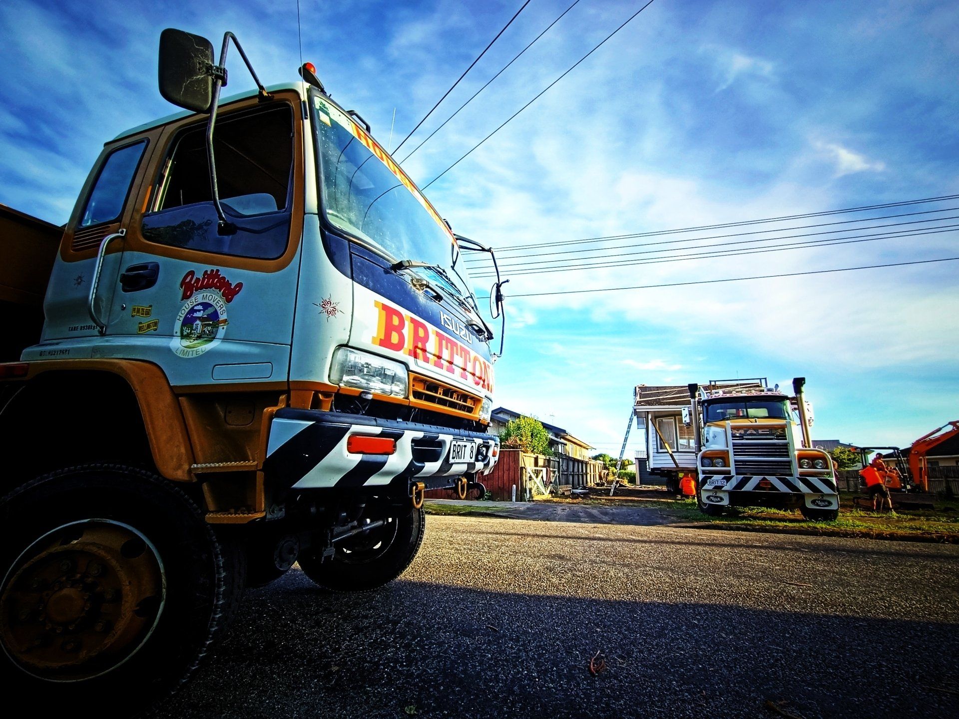 Two decorated trucks parked on a gravel lot under a bright blue sky