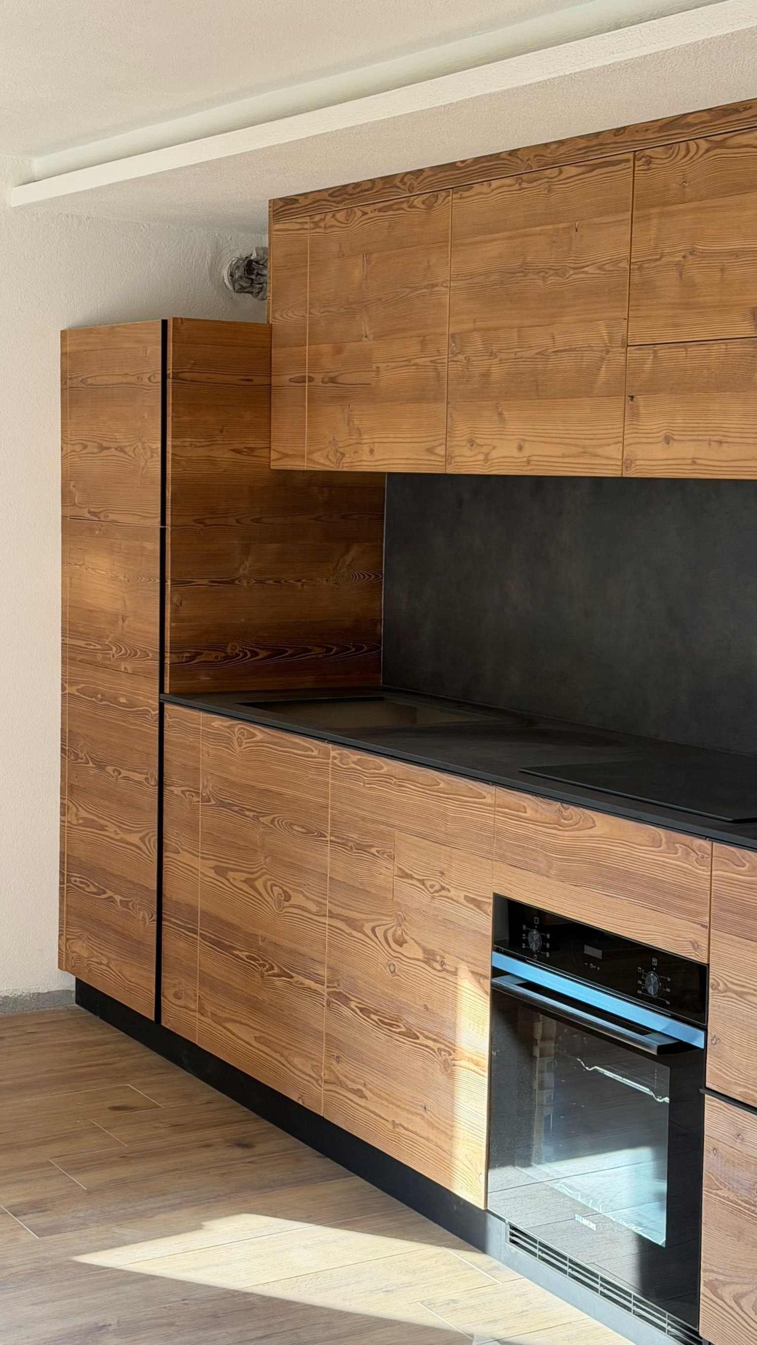 Pensili da cucina in legno con piano di lavoro nero e forno in acciaio inox