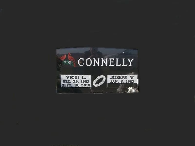 Connelly memorial plaque with red rose and two engraved nameplates on a dark background