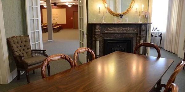 Formal dining room with a large wooden table, upholstered chairs, fireplace, and decorative mirror
