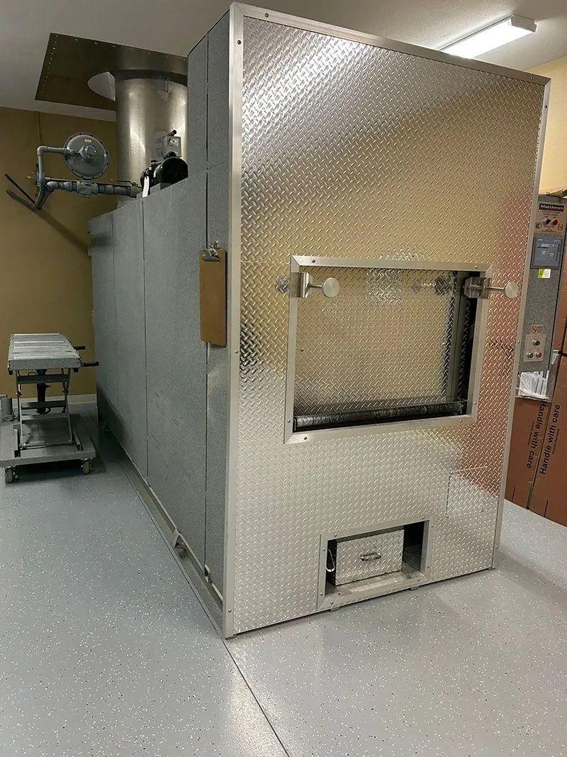 Large metallic industrial oven or chamber with a diamond-plate finish in a kitchen or workshop room