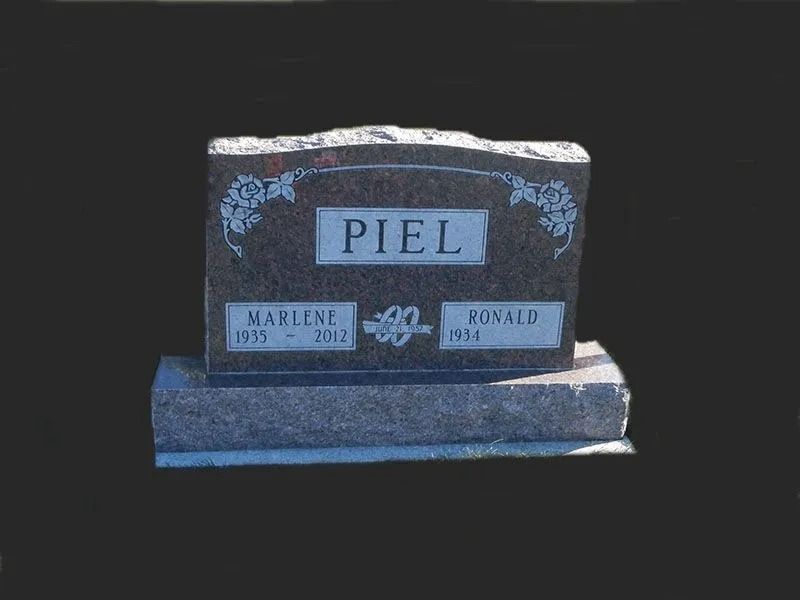 Granite headstone with the name “PIEL” and two smaller name plaques on a dark background