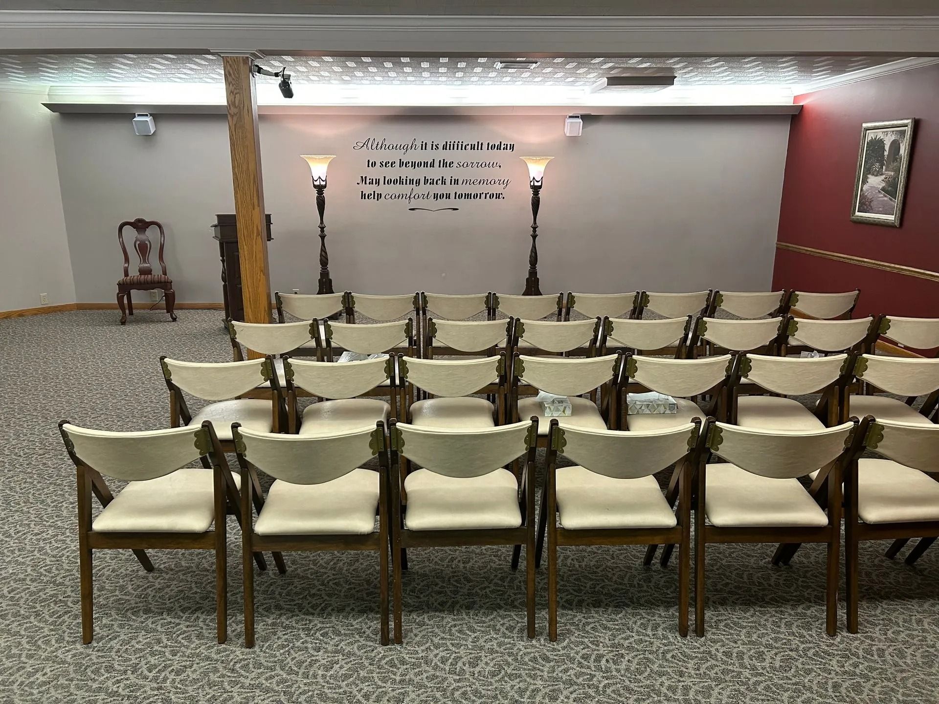 Conference room with rows of chairs facing a decorated front wall and podiums.