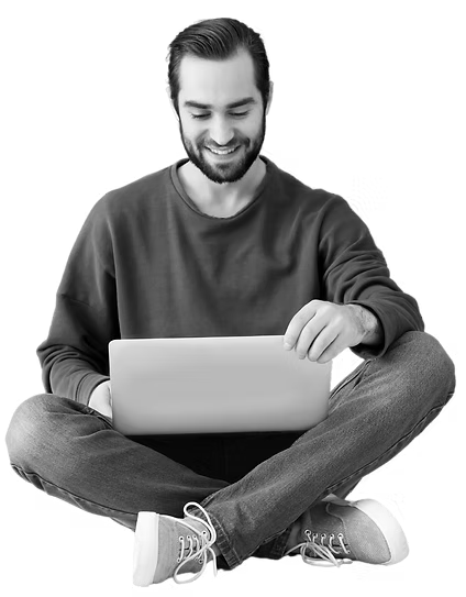 Smiling person sitting cross-legged with a laptop on their lap, looking down and typing