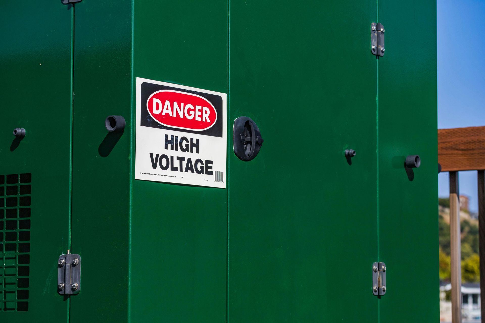 Danger High Voltage sign on a green electrical cabinet outdoors