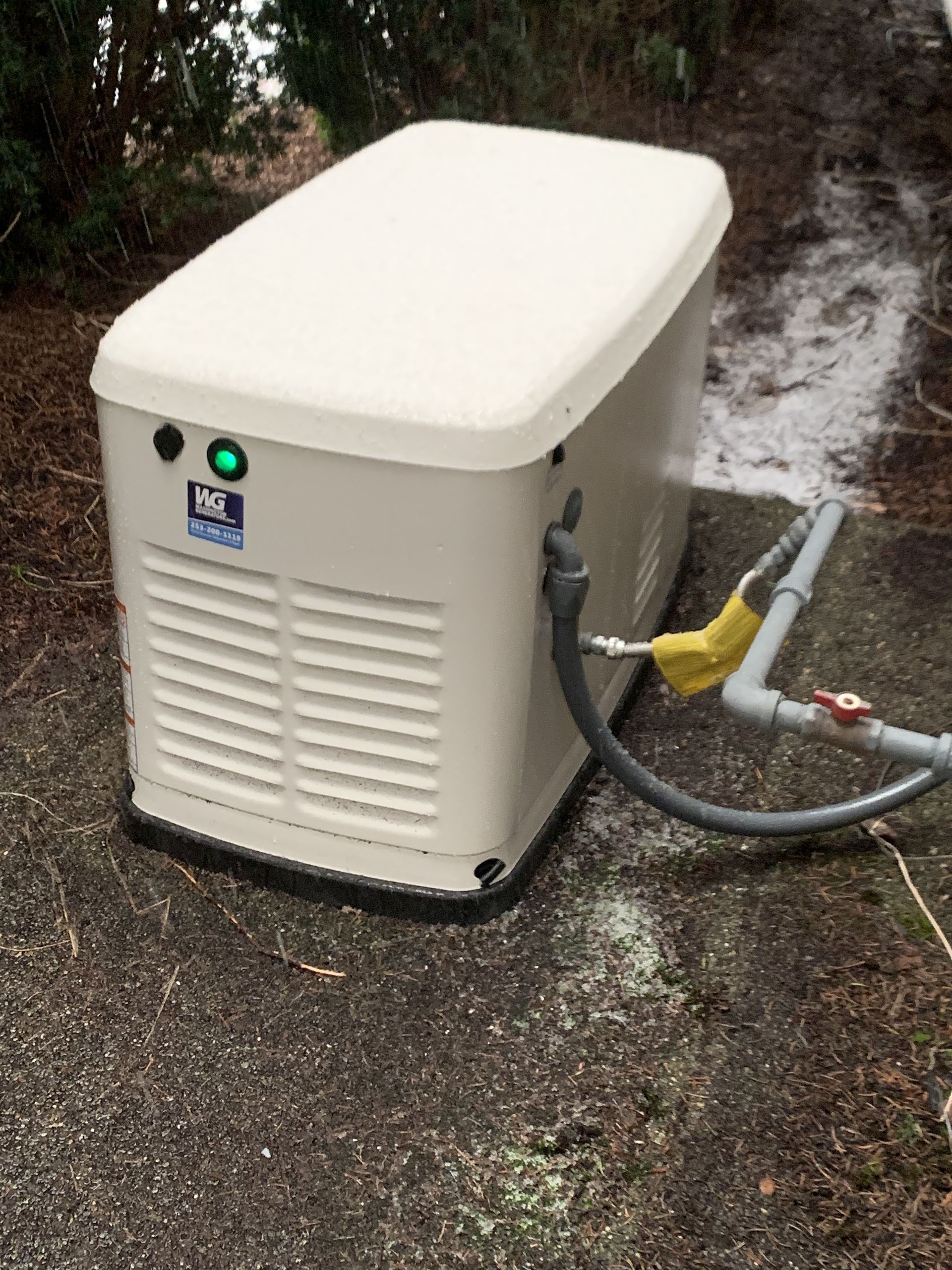 White generator unit on wet pavement with hoses attached and water spraying nearby