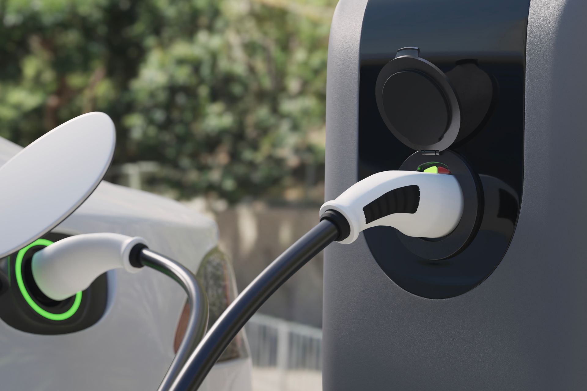 Close-up of an electric car charging plug connected to a charging station with green indicator lights.