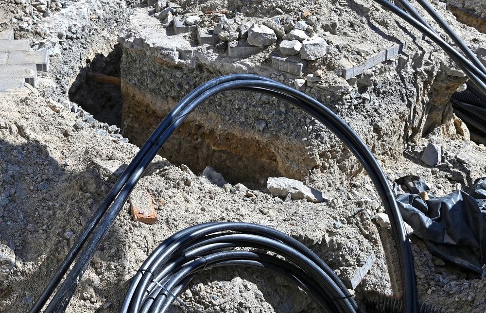 Black cables coiled on a rocky surface beside a narrow trench