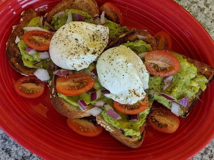 A red plate topped with avocado toast and poached eggs Afternoon Delight Restaurant Ann Arbor MI