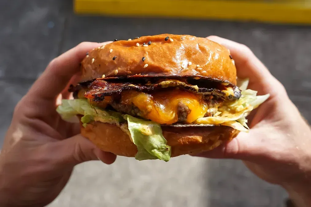 A person is holding a hamburger in their hands