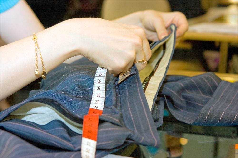 A person is measuring a piece of clothing with a tape measure