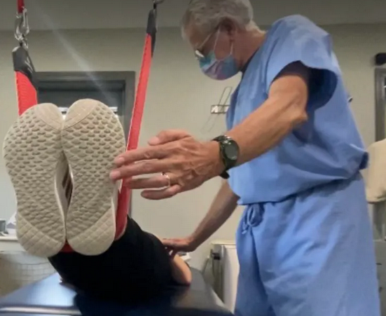 A man wearing a mask is helping a patient lift their legs