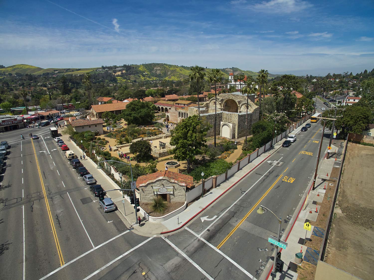 Aerial view of a town intersection beside a church and hillside neighborhoods on a sunny day