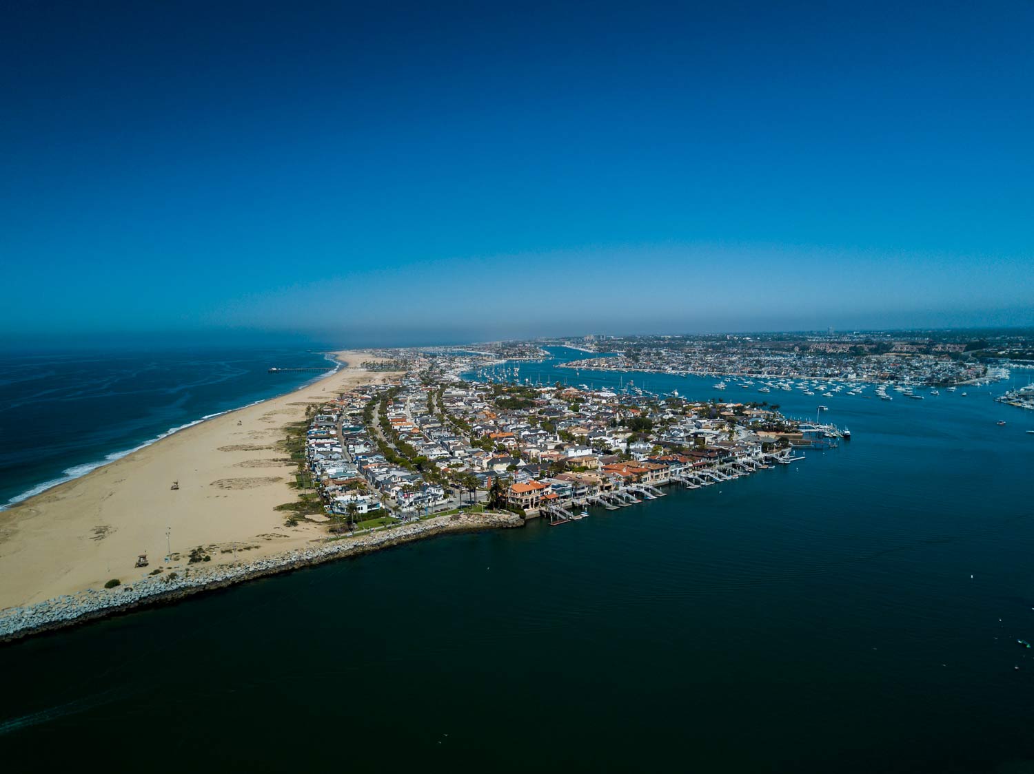 Aerial view of a sandy peninsula with houses, beaches, and blue ocean on both sides