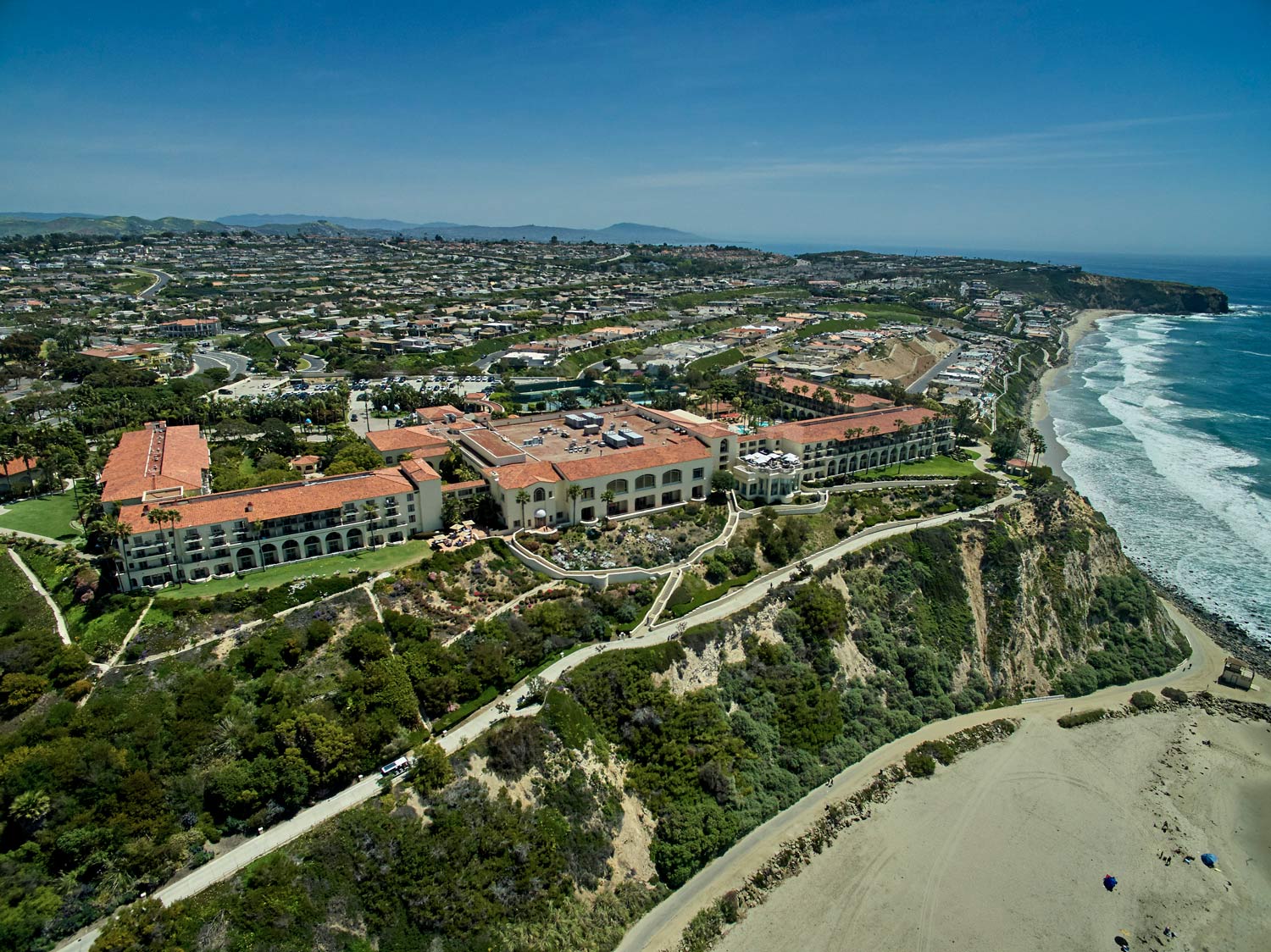 Aerial view of coastal resort buildings above a beach and ocean shoreline.
