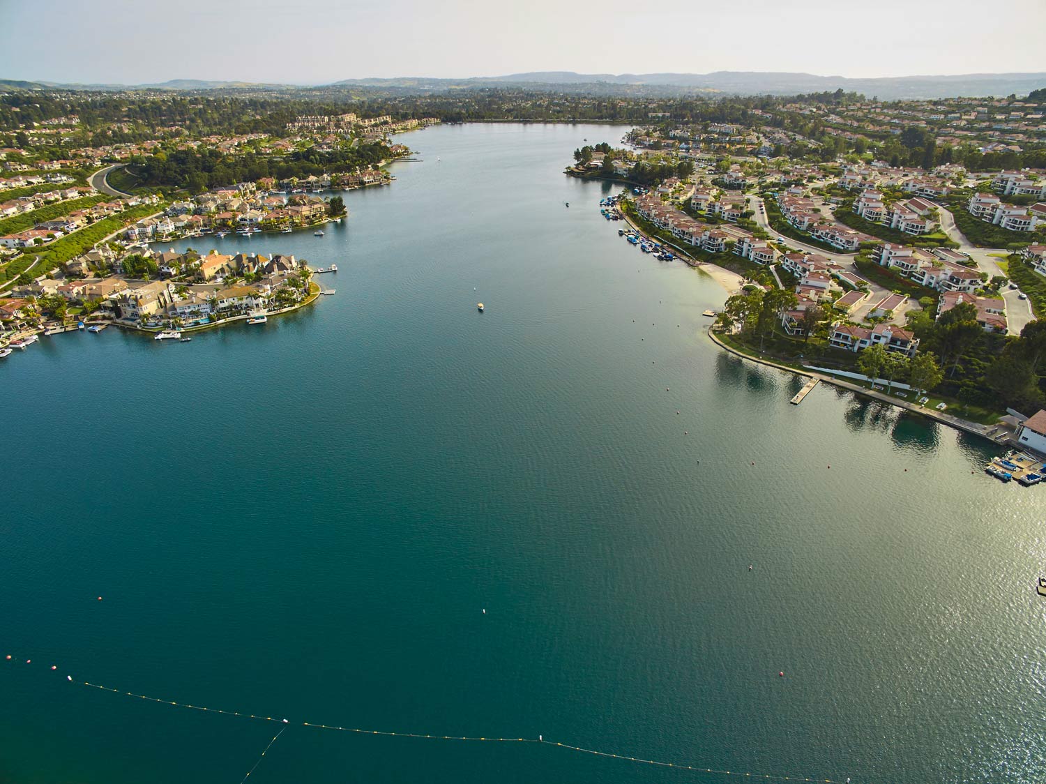 Aerial view of a wide blue lake bordered by dense suburban neighborhoods and greenery.
