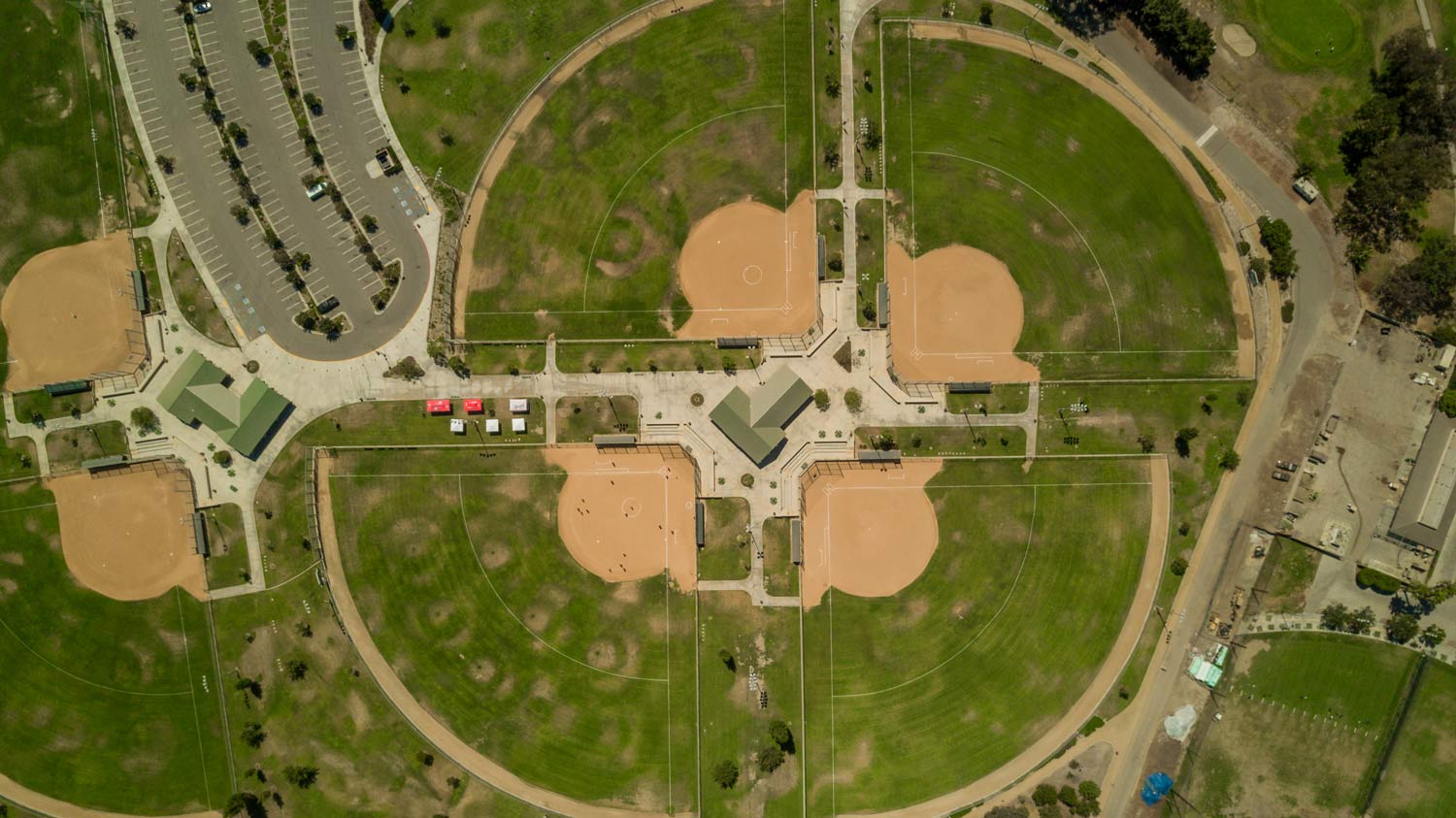 Aerial view of a baseball complex with several diamonds and parking lots surrounded by trees.