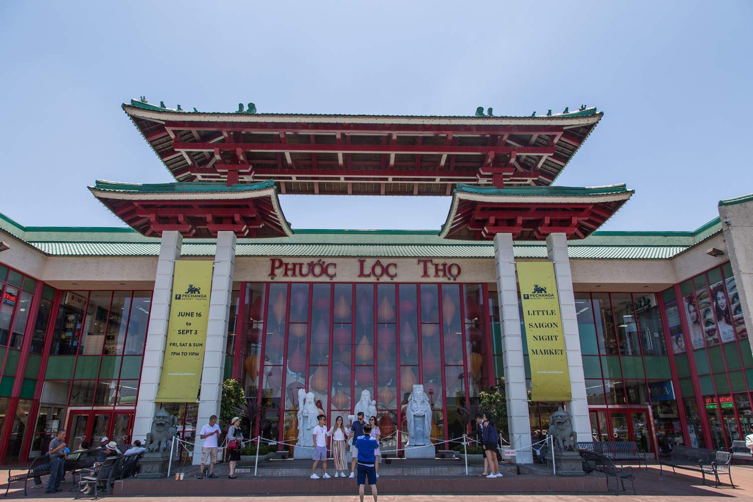 People posing at the entrance of Phuoc Loc Tho temple with red and green roof details
