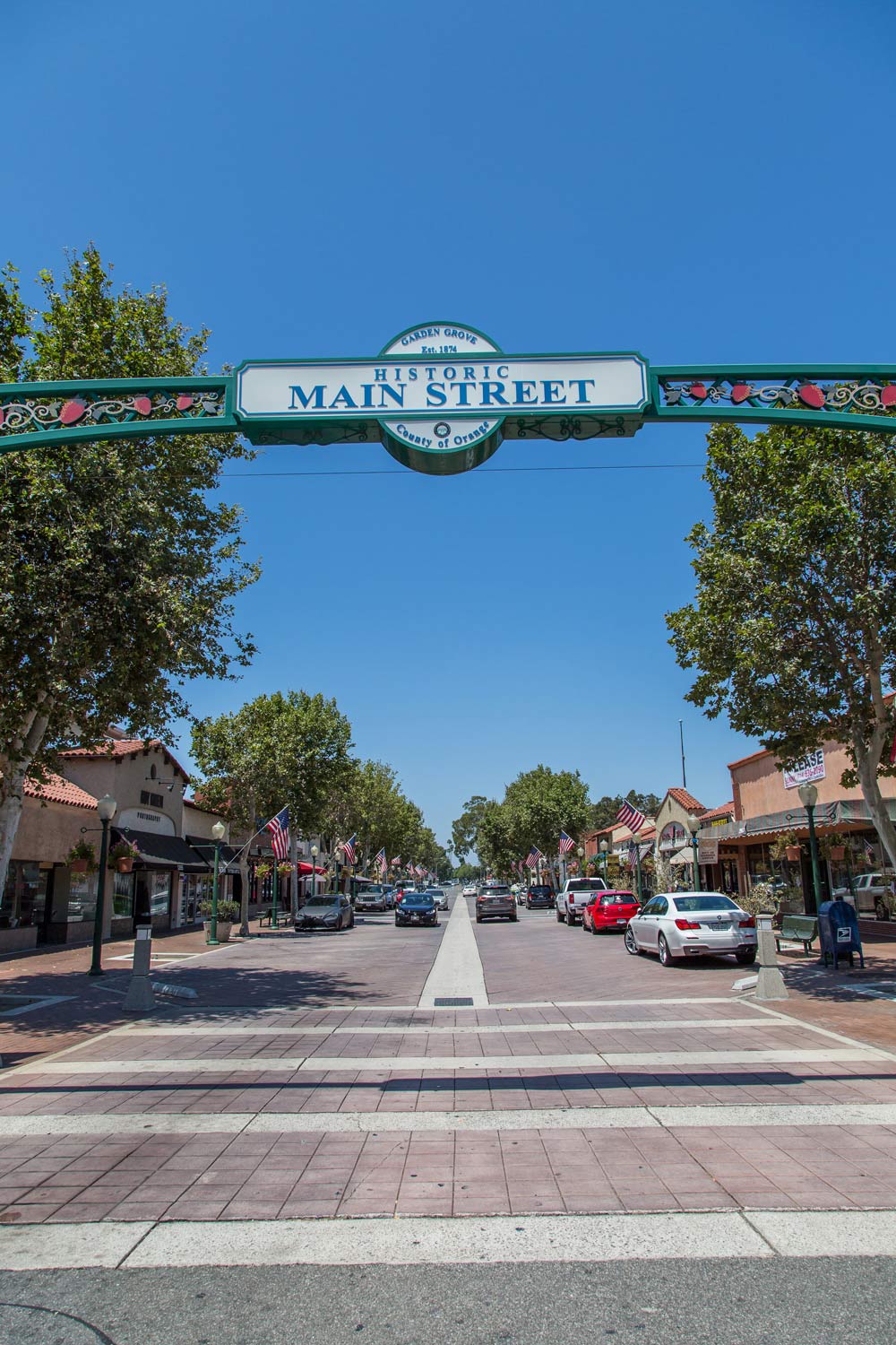 Main Street gateway over a sunny street with parked cars and storefronts
