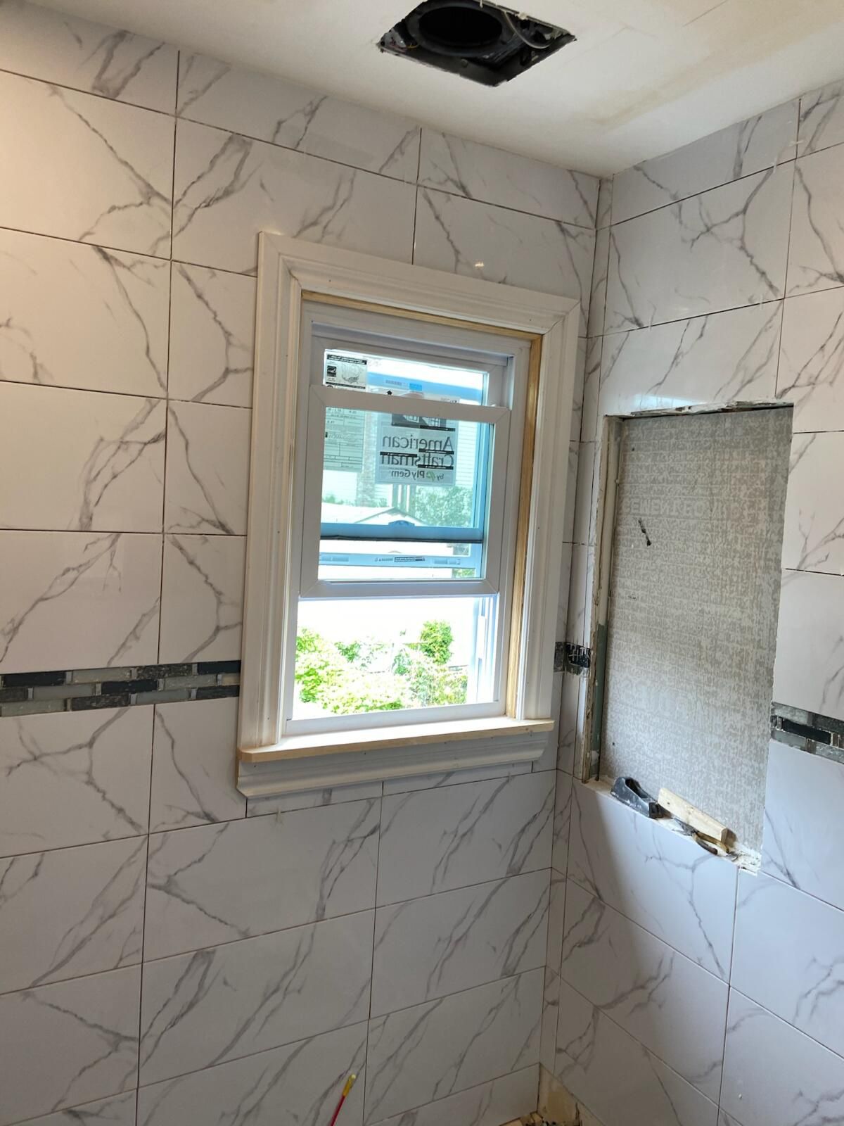 A bathroom with marble tiles and a window.