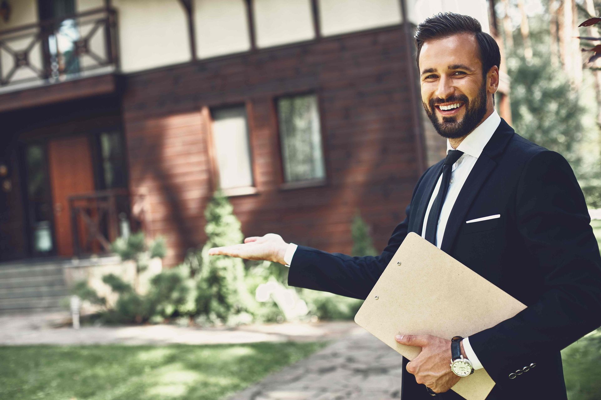A Realtor® standing in front of and gesturing at a house at Kentuckiana Real Estate Academy near Lexington, KY