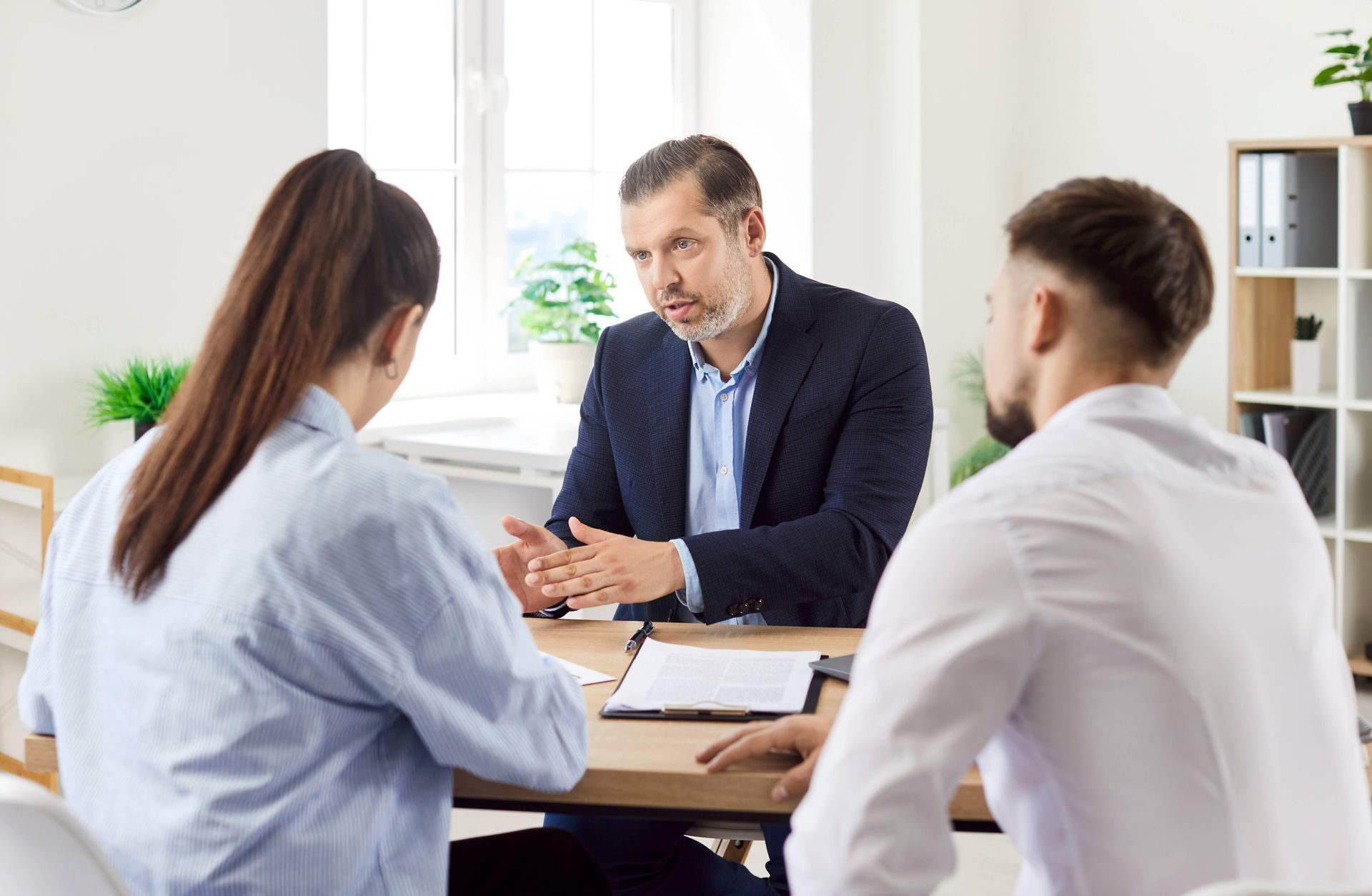 A real estate agent speaking with two homebuyers in an office at Kentuckiana Real Estate Academy near Lexington, KY